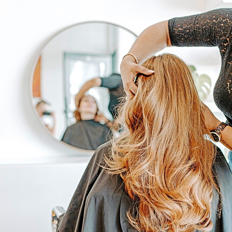 Stylist styling long highlighted hair at salon