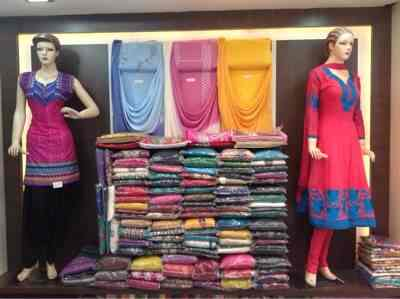 Mannequins with suit sets and fabric stacks at Lena Dena boutique