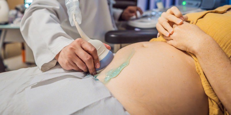 Pregnancy ultrasound scan in progress with gel on abdomen
