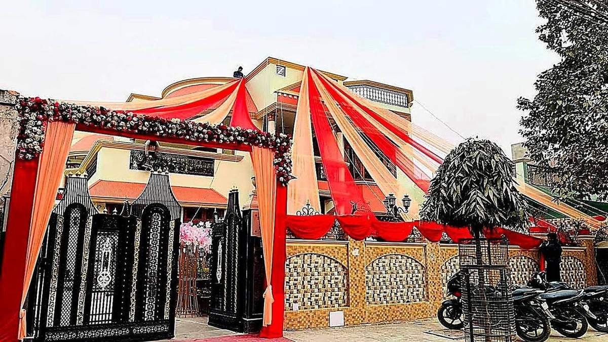 House exterior wedding decor with red drapes and floral entrance gate by Nits Events, wedding planner in Rajajipuram Lucknow