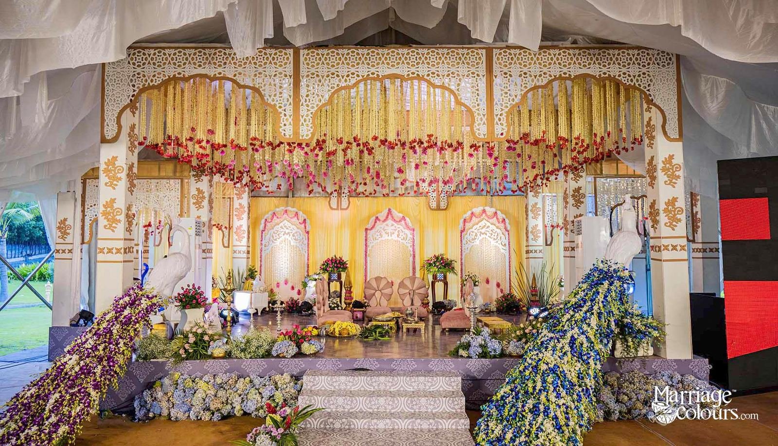 Grand wedding stage with floral chandeliers and peacock decor by Nits Events