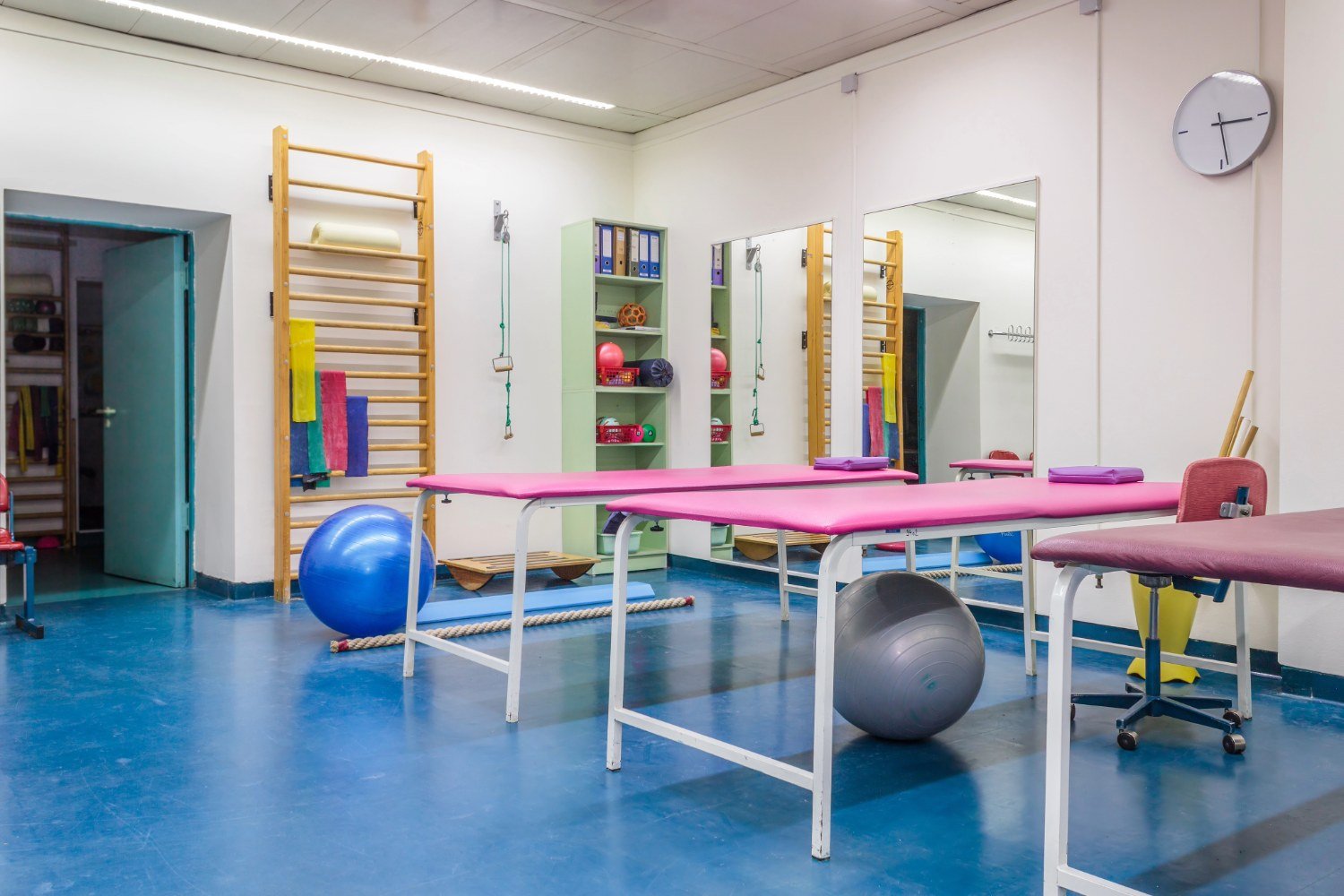 Modern physiotherapy exercise room with therapy balls and parallel bars