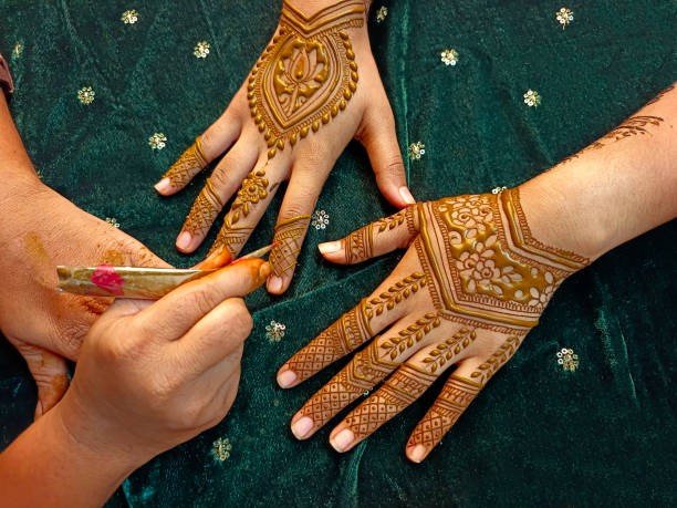 Mehndi artist applying henna cone on bride hands in Lucknow