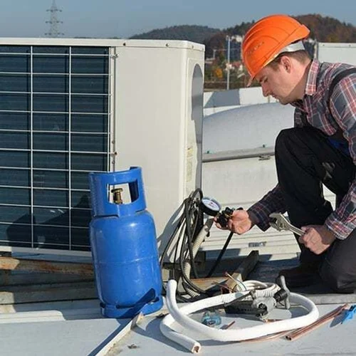 AC outdoor unit being serviced on a rooftop with gas cylinder — ac installation in Wazirbagh Mohallah, Lucknow